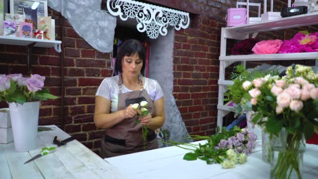Professionellen-Floristen-Reinigung-und-Inspektion-der-weißen-rose-Zweig-von-trockenen-Blütenblätter