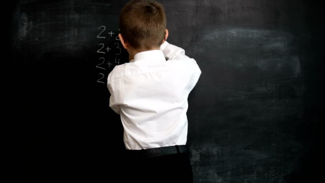 Young-boy-solving-maths-expression-on-a-blackboard.-Creative-concept-of-back-to-school-and-study.-Pre-school