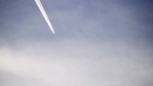 Footage,-using-a-telephoto-lens-of-an-airplane-flying-high-in-the-clouds.
