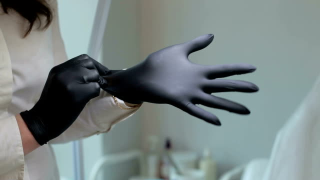 La-cosmetóloga-pone-negro-guantes-de-protección-en-la-sala-de-cosmetología.