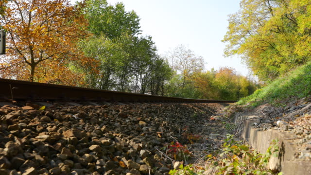 Eisenbahnschienen-Blick-ein-Blick-von-der-Strecke-aus-dem-Boden-während-der-Bewegung-langsam-nach-vorne-in-der-Nähe-der-lokalen-Gesamtstruktur-an-einem-sonnigen-Tag-am-Ende-des-Herbstes.