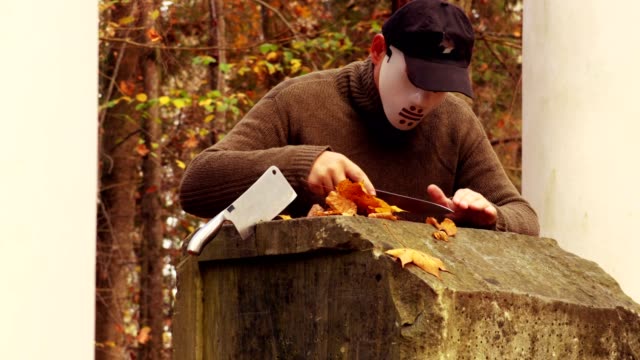Man-with-scary-Halloween-mask-sharpening-knives-in-park