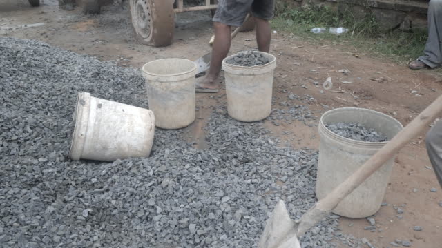 Using-a-shovel-to-put-gravel-into-a-bucket-(-close-up)