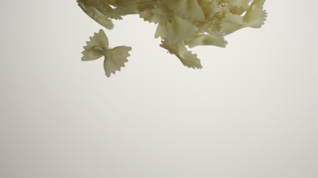 SLOW-MOTION:-Farfalle-Pasta-falls-under-water-on-white-background