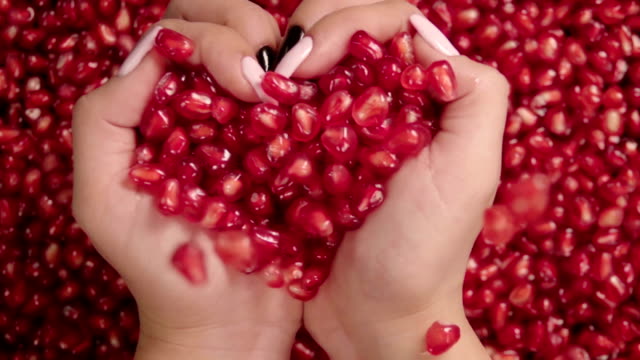 Falling-grains-of-pomegranate-into-the-hands-.-Slow-motion