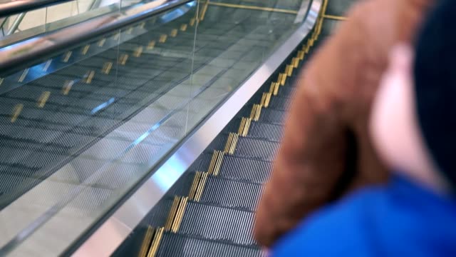 Mom-and-her-son-are-going-down-the-escalator.-They-are-in-winter-clothes,-came-to-the-mall