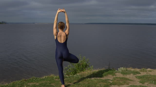 Mujer-de-yoga-en-ropa-deportiva-plantean-contra-lago