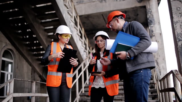 The-foreman-and-two-women-inspectors-to-discuss-the-plan-of-work-performed-on-construction-or-restoration-of-the-building.