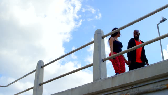 Happy-couple-interacting-with-each-other-while-walking-near-railing-4k