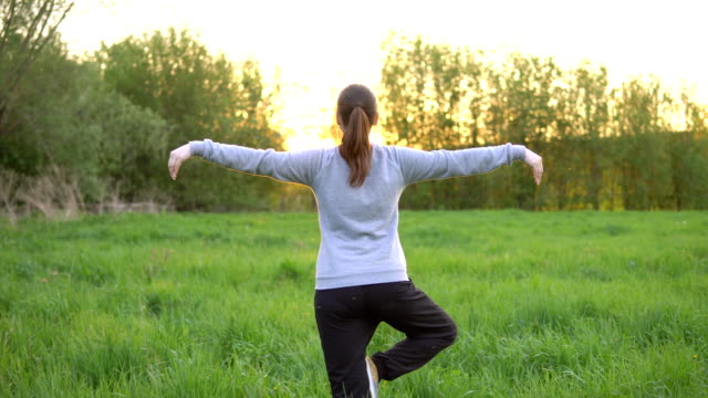 Young-woman-doing-exercises-in-the-field-at-sunrise