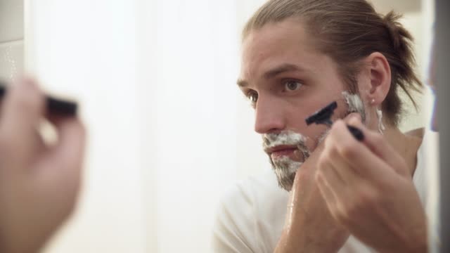 Hombre-afeitado-barba-con-navaja-en-baño