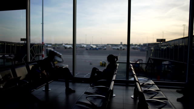 Male-and-female-passengers-sitting-at-departure-lounge,-waiting-for-plane