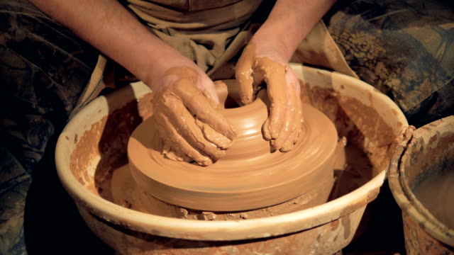 Potters-hands-make-a-wide-low-bowl-on-a-wheel.