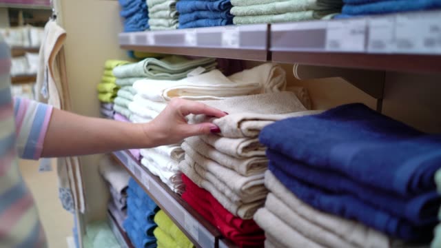 Caucasian-woman-near-shop-shelves-choosing-towel-in-store-closeup