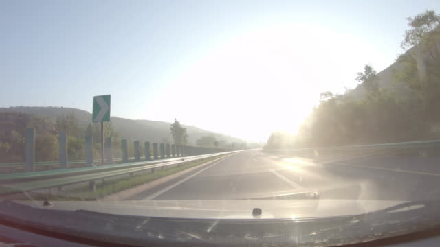 Conducir-coche-en-autopista-del-sol-del-amanecer,-parabrisas-delantero-POV,-destello-de-lente