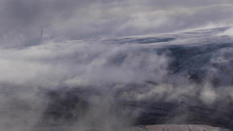 nubes-bajas-deriva-además-de-montañas-durante-salida-del-sol,-mostrando-molinos-de-viento-en-la-Escocia
