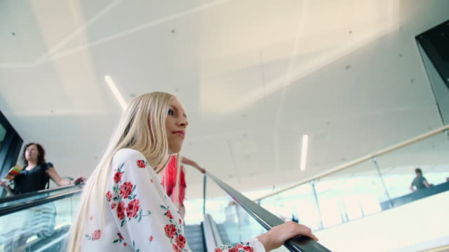 Young-blonde-woman-riding-on-escalator