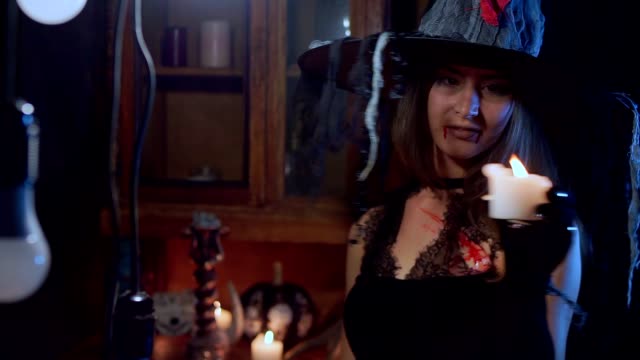 Halloween-Hexe-mit-Hut-nimmt-eine-Kerze-in-der-Hand-und-bläst-es-aus.