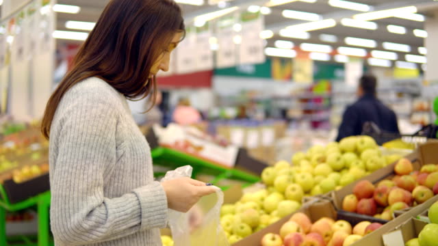 Mujer-joven-en-el-Departamento-de-verdura-de-un-supermercado-es-escoger-manzanas