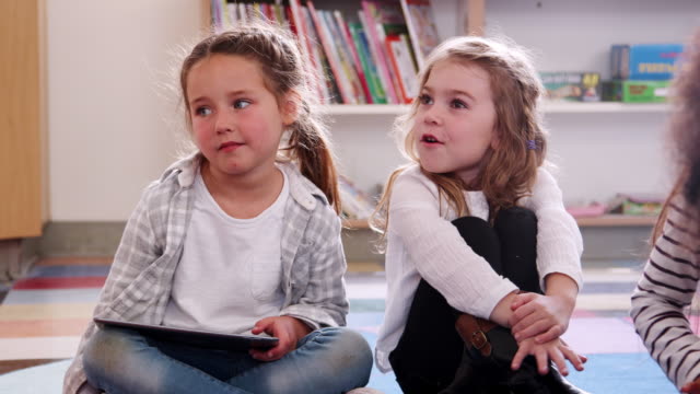 Zwei-elementare-Schulmädchen-mit-Tablet-Computer-im-Unterricht