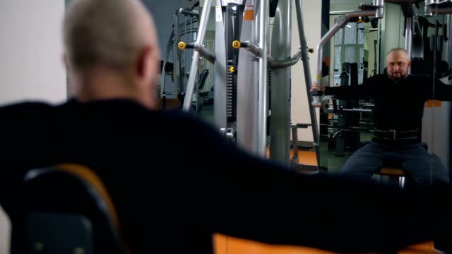 Strong-man-in-the-gym-shakes-hands.-Reflection-in-the-mirror-4K-Slow-Mo