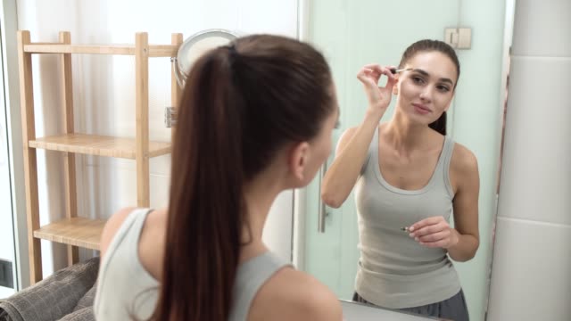 Schönheit-Make-up.-Frau-Bürsten-Augenbrauen-am-Badezimmerspiegel