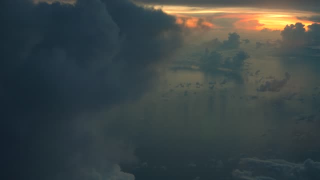 Vista-aérea-de-nubes-blancas-sobre-cielo-azul-en-la-salida-del-sol-con-el-reflejo-en-el-océano