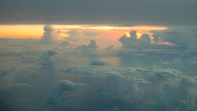 Vista-aérea-de-nubes-blancas-sobre-cielo-azul-en-la-salida-del-sol-con-el-reflejo-en-el-océano