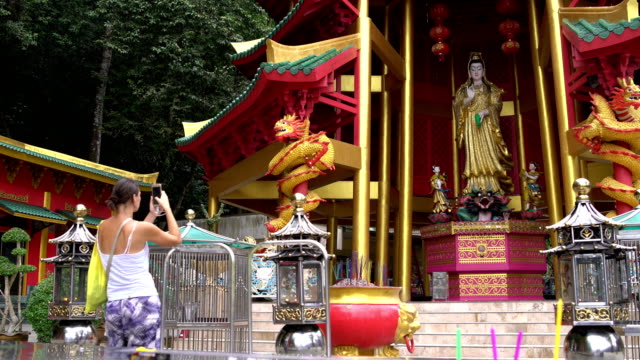Eine-Frau-ist-eine-Statue-einer-Gottheit-in-einem-buddhistischen-Tempel-fotografieren.