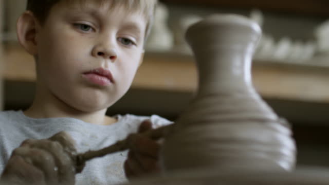 Boy-Decorating-Clay-Vase-in-Pottery-Workshop