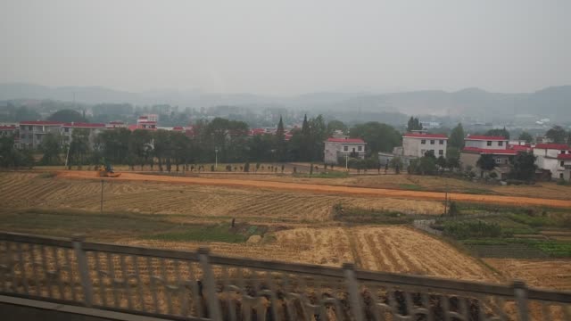 Side-view-from-a-passenger-train-of-the-countryside-of-China,-fast-motion-mode.