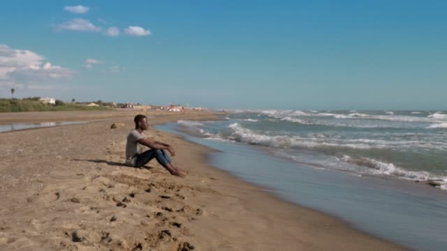 paz,-naturaleza,-relax.-Joven-negro-a-americano-sentado-en-el-océano-obersving-de-playa