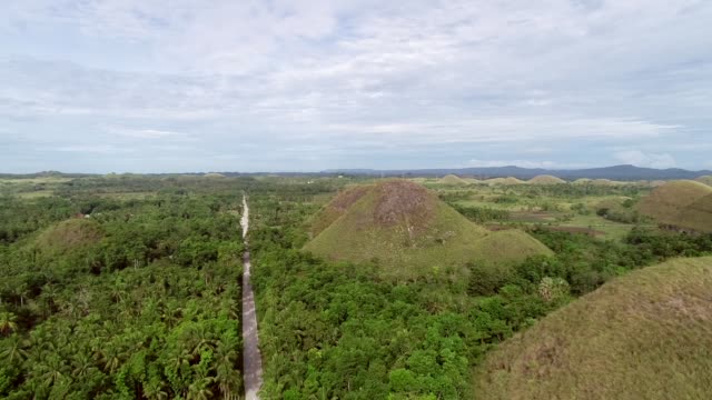 Camino-vista-aérea-cruzando-el-complejo-de-colinas-de-Chocolate,-Batuan,-Filipinas.