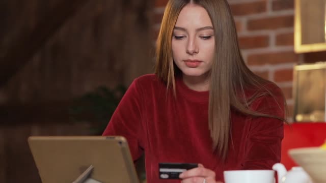 Mujer-joven-haciendo-compra-tarjeta-de-crédito-en-línea,-escribir-los-datos-en-tabletPC-en-la-cocina-moderna