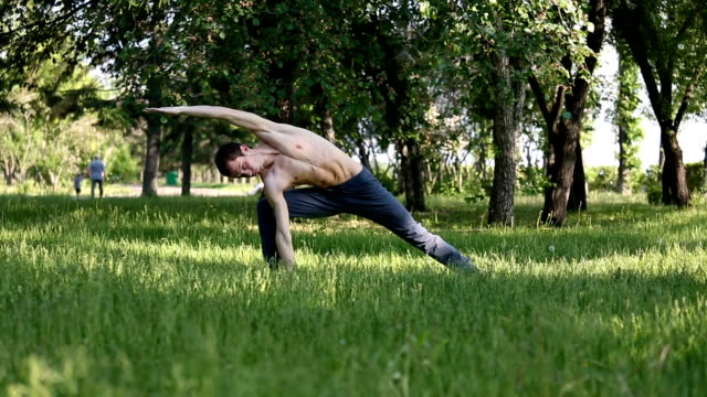 Schlanke-junge-Mann-praktizieren-Yoga-im-park