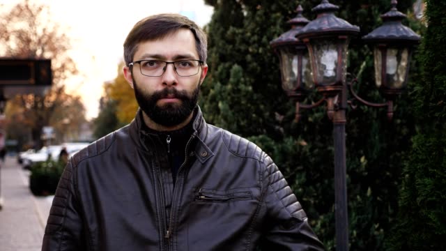 Portrait-of-young-attractive-bearded-man-in-glasses-and-looking-at-the-camera.-Man-with-poker-face-making-thumbs-down,-slow-motion
