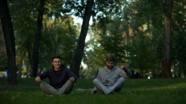 Dos-amigos-meditando-en-el-parque-central,-lotus-plantean,-asanas-de-yoga,-la-búsqueda-de-la-armonía
