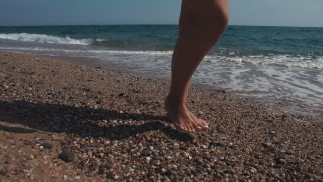 Mujer-caminando-en-la-playa-de-guijarros.