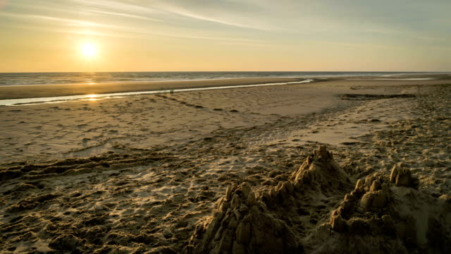 Zeitraffer-von-einem-Sonnenuntergang-am-Strand-von-Lacanau-mit-eine-Sandburg,-Frankreich