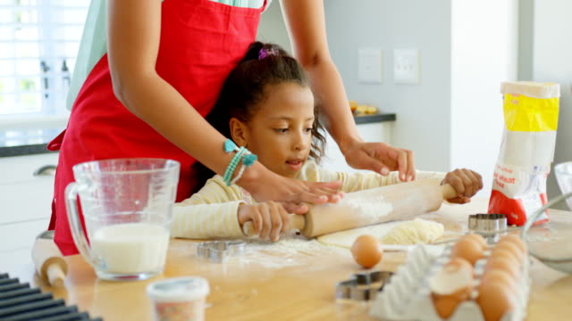 Front-view-of-black-mother-and-daughter-rolling-dough-with-rolling-pin-at-home-4k
