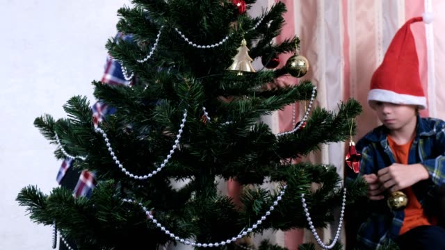 Mutter-und-Sohn-in-Weihnachtsmützen-schmücken-Weihnachtsbaum-mit-Perlen-und-Kugeln.