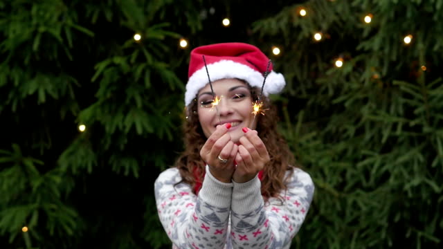 junge-Frau-auf-dem-Hintergrund-der-Weihnachtsbaum-und-Girlanden-mit-sparklers.fun-und-Sprünge