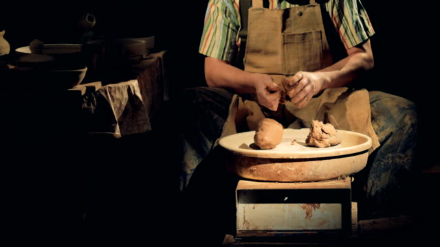 An-unrecognizable-potter-in-a-dark-studio-kneads-clay.
