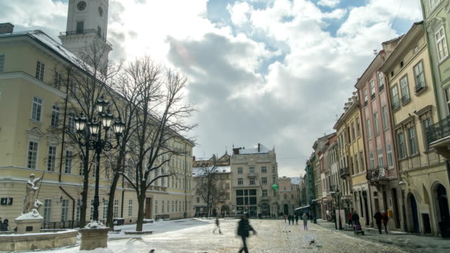 LVOV,-Ucrania---Timelapse-de-invierno-2018:-Centro-de-la-vieja-ciudad-de-Lviv,-Ucrania.-Lapso-de-tiempo-de-mover-gente-a-través-de-la-Plaza-del-mercado-(Ploshcha-Rynok)-cerca-del-Ayuntamiento.-Las-nubes-se-están-moviendo-rápidamente.