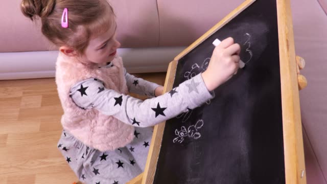 Little-girl-is-drawing-on-a-blackboard