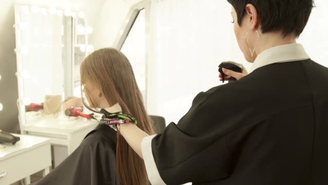 Hairdresser-spraying-water-on-long-hair-female-haircut-in-hairdressing-salon.-Female-hairstyle-in-beauty-salon.-Haircutter-working-with-client-close-up