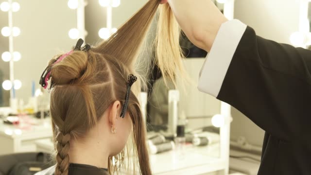 Hairstylist-combing-strand-hair-and-spraying-water-before-cutting-in-beauty-salon.-Close-up-hairdresser-making-female-haircut-in-hairdressing-salon