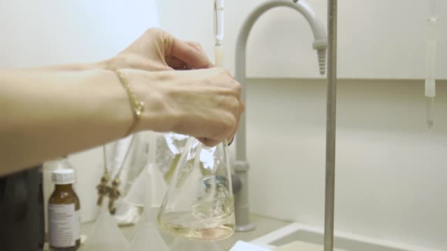 Chemische-Fläschchen-mit-bunten-Flüssigkeiten-schütteln-im-Labor