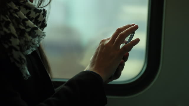 Primer-plano-de-mujer-sosteniendo-el-dispositivo-smartphone-mientras-viaja-en-tren.-Persona-navegando-por-internet-y-revisar-correos-electrónicos-en-el-transporte