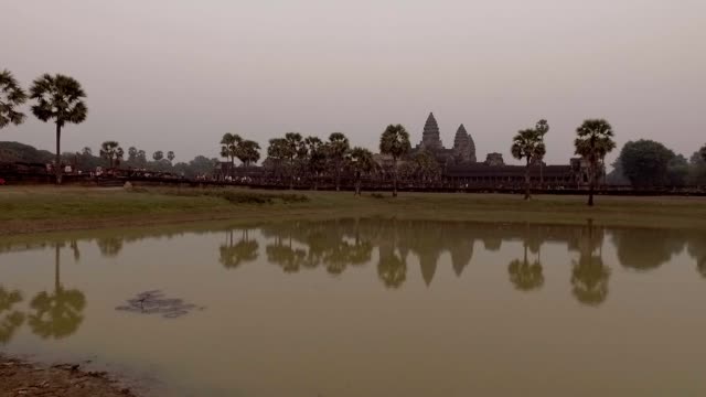 Kamerafahrt-in-Angkor-Wat-Tempel-bei-Sonnenaufgang-mit-Massen-von-Menschen-betreten-der-Anlage-auf-der-Seite